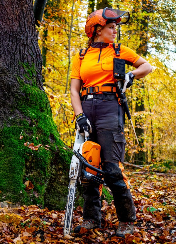 Forstwirtin mit Profi-Forstgürtel von Fuegos, ausgestattet mit einer Stihl-Kettensäge im herbstlichen Wald